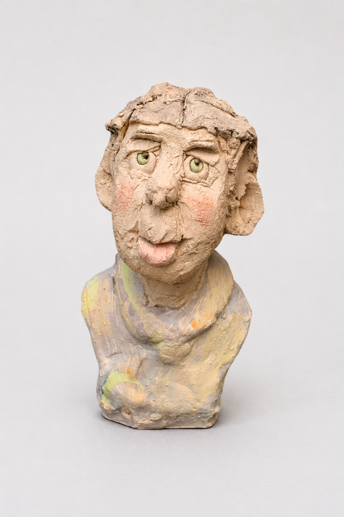 tête en grès chamotté et engobes d'un homme au regard vert, joues rosées expression malicieuse et visage naïf dans des tons pastels